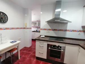 - une cuisine avec des murs blancs et une cuisinière four supérieur dans l'établissement Keka en Playa la Victoria con Ascensor Grupo AC Gestion, à Cadix