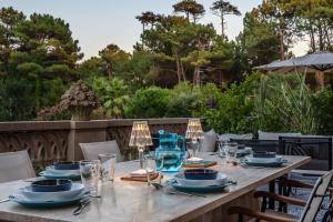 a wooden table with plates and glasses on a patio at Splendide Appartement de charme avec vue sur le Golf, proche plage et terrasse in Anglet