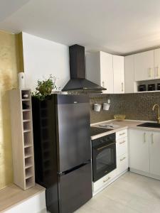 eine Küche mit einem schwarzen Kühlschrank und weißen Schränken in der Unterkunft Studio apartman Piccolo in Metković