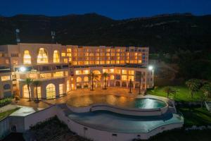 a large building with a swimming pool at night at Royal Tulip Korbous Bay Thalasso & Springs in Qurbuş