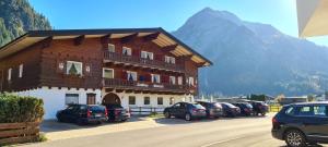 a large building with cars parked in a parking lot at Landhaus Almrausch in Mittelberg