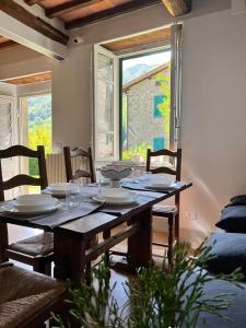 een eettafel met stoelen en een groot raam bij La Casina del Bassotto in Bagni di Lucca