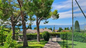 a fence in front of a yard with trees at APARTMENT BREZZA DI LAGO - Regarda Travel in Lazise