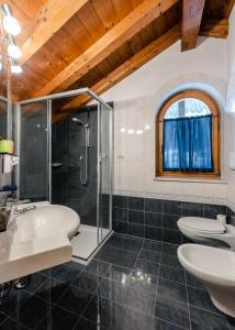 a bathroom with a sink and a shower and two toilets at dalaNat in Corvara in Badia