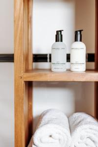 a shelf with three bottles of soap and towels at B&B Buytenlust in Rockanje