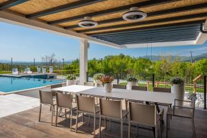 eine Terrasse mit Tisch und Stühlen und einem Pool in der Unterkunft Luxury Villa Arya with 77sqm heated pool, hot-tub, sauna, gym, billiard, playgrounds, 6 bedroom in Bajagić