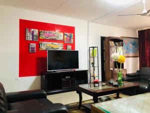 Serenity plus في آكرا: غرفة معيشة مع تلفزيون بشاشة مسطحة على جدار