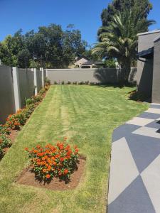 a garden with orange flowers in a yard at URlyfstyle Cottage Near OR Tambo International Airport in Kempton Park