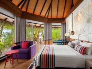 Un dormitorio con una cama grande y una silla morada en Mercure Maldives Kooddoo Resort en Gaafu Alifu Atoll