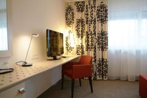 a living room with a tv and a chair at Hotel Schwanen Stuttgart Airport/Messe in Filderstadt