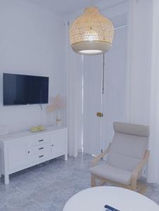 ein Wohnzimmer mit einem Stuhl und einem TV in der Unterkunft VACATIONAL HOMES South Organic in Málaga
