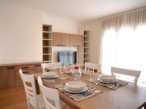 a dining room with a wooden table and white chairs at Nido della Poiana - Attico PANORAMICO in Grado