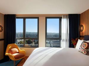 a bedroom with a bed and a chair and windows at SO Paris Hotel in Paris