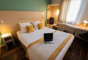a hotel room with a bed with a laptop on it at Kyriad Lyon Est - Bron Eurexpo Le Cottage in Bron