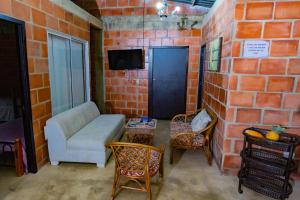 a living room with a couch and chairs and a brick wall at LAS ORQUIDEAS in Rozo