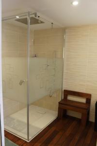 El baño incluye una ducha acristalada con banco. en Petite maison chaleureuse avec jacuzzi privatif, en Savigny-sous-Mâlain