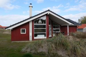 une maison rouge avec de grandes fenêtres dans un champ dans l'établissement Resort 2 Sea Lodge C 112, à Großenbrode