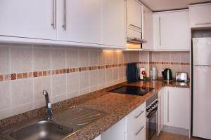 Una cocina con gabinetes blancos y un fregadero. en Penthouse Alcalá 1, en Alcalá