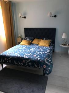 a bedroom with a bed with a blue floral comforter at Chambre d'hôte La Clef du Bonheur in Longuenesse