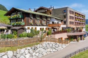 ein Haus in den Bergen mit einem Zaun in der Unterkunft Familotel Alphotel in Hirschegg