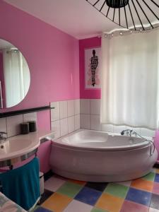 uma casa de banho cor-de-rosa com uma banheira e um lavatório. em Chambre d'hôte La Clef du Bonheur em Longuenesse