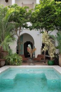 uma piscina em frente a uma casa com árvores em Riad Al Massarah em Marraquexe