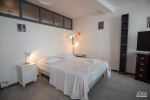 Schlafzimmer mit einem weißen Bett und einem TV in der Unterkunft Hyper centre - wifi - cosy - Gare in Bourg-en-Bresse