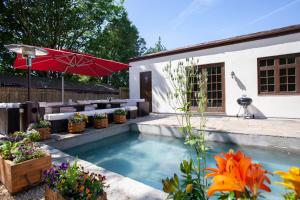 una piscina con una sombrilla roja y algunas flores en La Villa Olli -Natural pool & Hot tub en Bristol