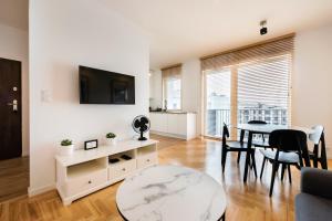 ein Wohnzimmer mit einem Tisch und einem TV in der Unterkunft Apartament Lekka in Warschau