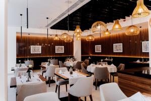 a restaurant with white tables and chairs and chandeliers at Grand Ascot Hotel in Krakow