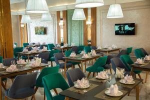 Un comedor con mesas y sillas verdes. en Turon Telecom Hotel, en G‘azalkent