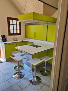 a kitchen with green cabinets and a counter with stools at Appartement Boutx in Boutx