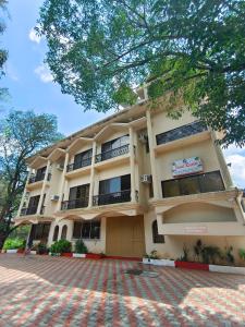 un grand bâtiment avec un arbre devant dans l'établissement Jewel Resort, à Lonavala