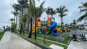 a playground with a slide in a park with palm trees at Salinas Premium Resort in Salinópolis