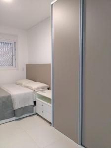 Habitación con 2 camas y puerta corredera de cristal en Espelho das Aguas Residence, en Florianópolis