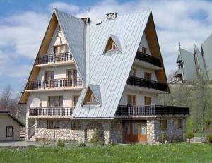 une grande maison avec un toit blanc dans l'établissement Domki i pokoje Toporówka, à Zakopane