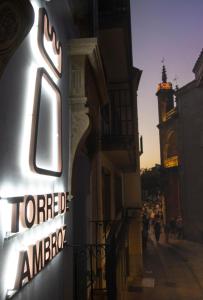 una señal en el lateral de un edificio con una torre de reloj en Torre de Ambroz, en Plasencia