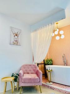 a bathroom with a pink chair and a bath tub at Virawan pool kohlarn วิราวัน พลู รีสอร์ต ที่พักเกาะล้าน in Ko Larn