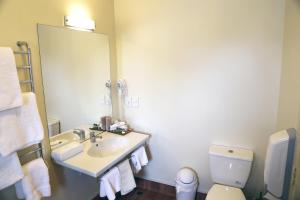 a bathroom with a sink and a toilet and a mirror at Abbots Hamilton – Hotel and Conference Centre in Hamilton