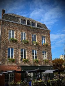 un edificio de ladrillo con ventanas y plantas. en Maison cosy avec jardin en plein centre historique, en Orbec-en-Auge