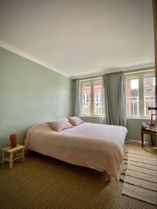 1 dormitorio con 1 cama grande y 2 ventanas en Maison cosy avec jardin en plein centre historique, en Orbec-en-Auge