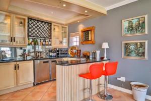 a kitchen with a counter and red chairs in it at Apartments Hout Bay in Cape Town