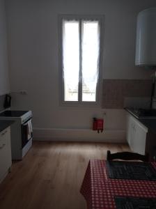 een lege keuken met een raam en een houten vloer bij antoinette in Carcassonne