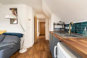 a kitchen with a couch and a sink in a room at Top Floor Flat on Harbour Street with sea views in Whitstable