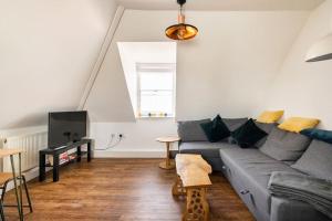 a living room with a gray couch and a tv at Top Floor Flat on Harbour Street with sea views in Whitstable