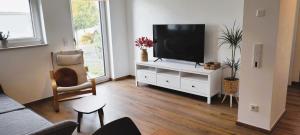 uma sala de estar com televisão num armário branco em Wine & Hike em Wincheringen