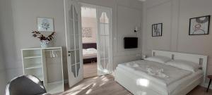 biała sypialnia z łóżkiem i telewizorem w obiekcie Castle Apartman **** w mieście Sátoraljaújhely