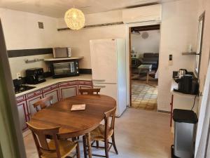 una cucina e una sala da pranzo con tavolo e sedie di Maison avec rivière, piscine, SPA, SAUNA Infrarouge,terrain boules, ping-pong, volley et Badminton a Sainte-Tulle