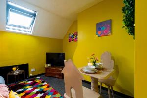 uma sala de estar amarela com uma mesa e uma televisão em Jesouth Charming Superb Comfortable Pretty Studio Pad Wifi em Hull