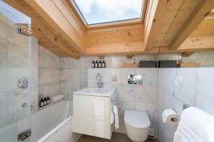 een badkamer met een wastafel, een toilet en een dakraam bij Chalet Melilot in Verbier